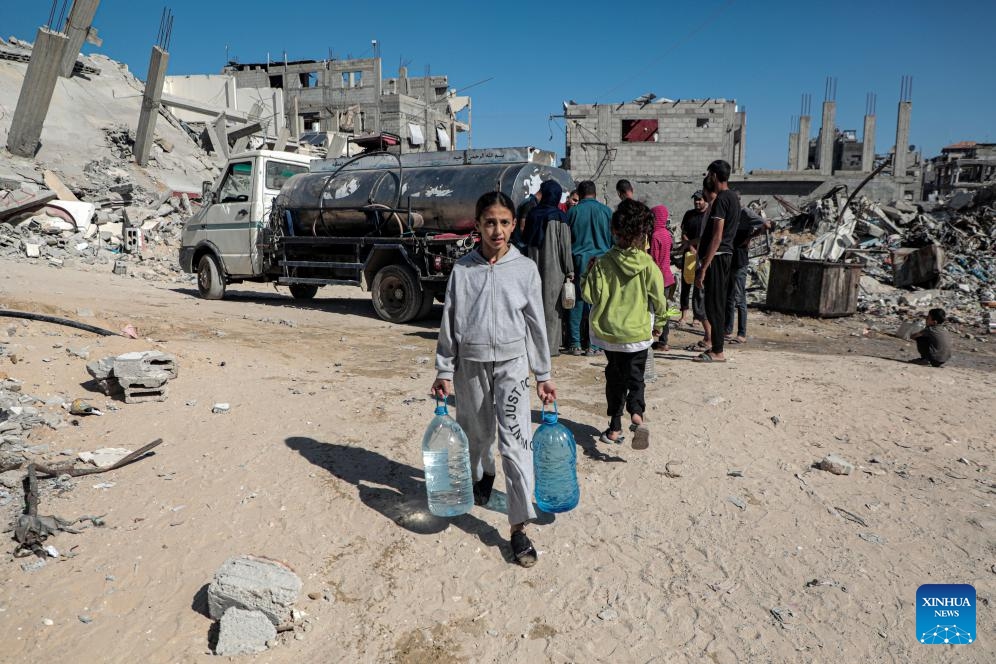 A Palestinian child returns home after filling bottles with water from a vehicle distributing free water, in the southern Gaza Strip city of Khan Younis, on Oct. 20, 2024. (Photo: Xinhua)