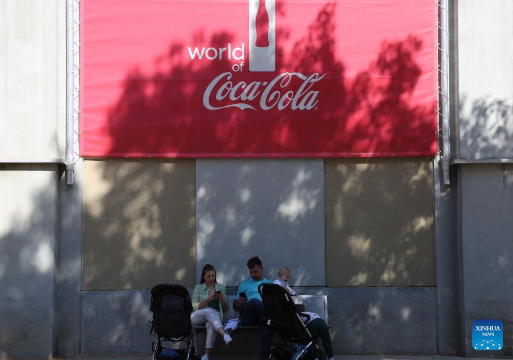 Visitors rest under a Coca-Cola logo at the World of Coca-Cola in Atlanta, Georgia, the United States, on Oct. 23, 2024. Coca-Cola shares fell nearly 2 percent on Wednesday after the company reported weaker-than-expected third-quarter unit case volumes. (Photo: Xinhua)