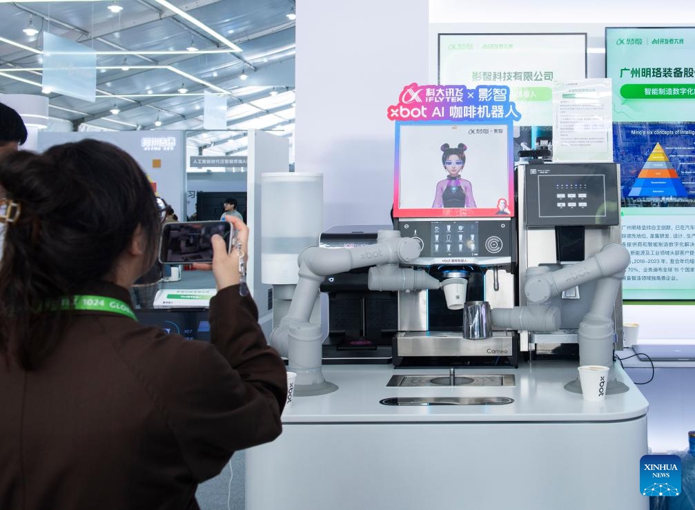 A visitor takes pictures of an AI-driven coffee-making robot at the 7th World Voice Expo in Hefei, east China's Anhui Province, Oct. 24, 2024. The 7th World Voice Expo and the iFlytek 1024 Global Developer Festival kicked off here on Thursday. The latest achievements and application of AI technology will be on display at the four-day event. (Photo: Xinhua)