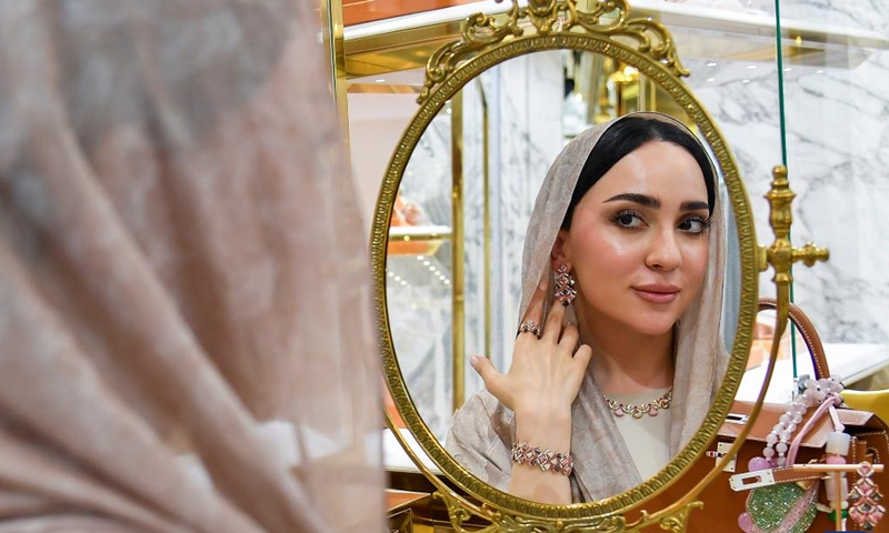 A woman tries handcrafted jewelry at a stall during the ASJAD Jewelry Exhibition at Alhazm Mall in Doha, Qatar, Oct. 24, 2024. The exhibition is held here from Oct. 24 to 29. (Photo: Xinhua)