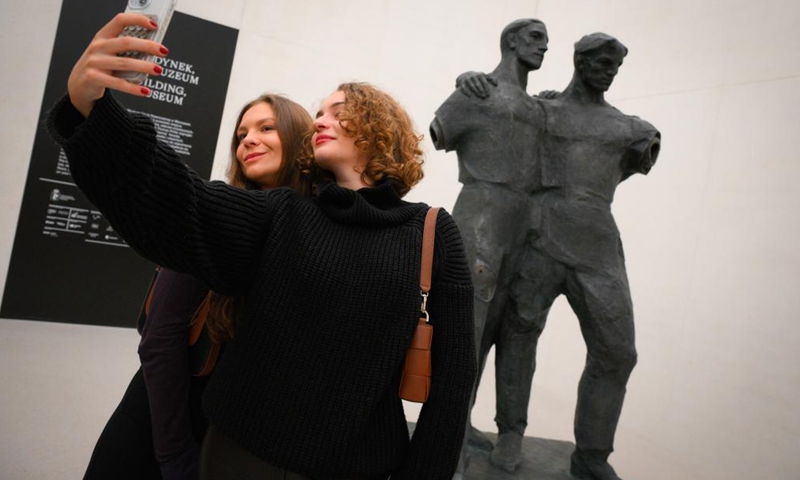 Two visitors take selfies with a sculpture displayed in the new building of Museum of Modern Art in Warsaw, Poland on Oct. 25, 2024. (Photo: Xinhua)