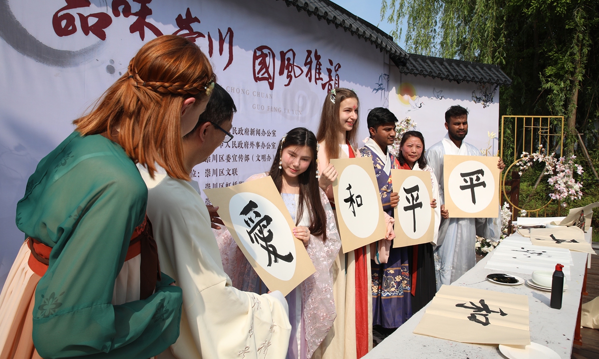 Foreign visitors showcase their calligraphy works featuring the Chinese characters conveying 