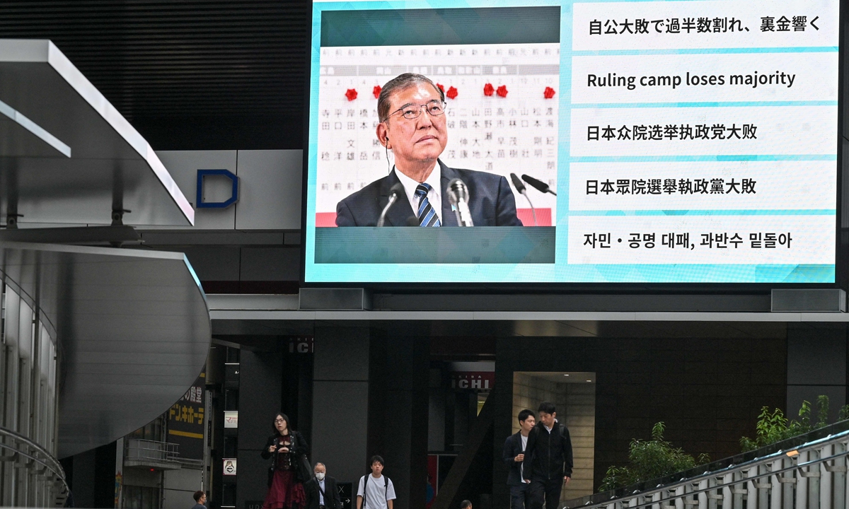 People walk along an elevated walkway under a large television screen showing images of Japan's Prime Minister Shigeru Ishiba one day after the general election in Tokyo on October 28, 2024. Photo: VCG