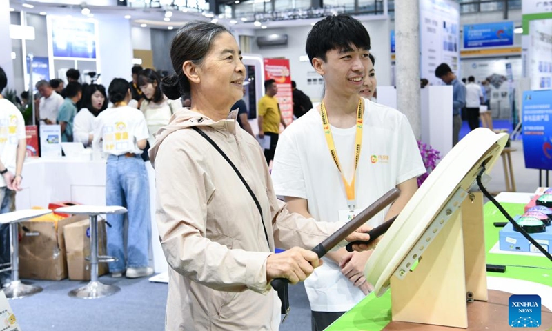 A senior woman tries her hands on a recreational musical instrument at the 2024 Shenzhen International Intelligent Elderly Care Industry Expo in Shenzhen, south China's Guangdong Province, Oct. 27, 2024. A total of 203 exhibitors from home and abroad have brought more than 1,000 products and technologies for elderly care to the expo, which was held from Oct. 25 to 27 in Shenzhen. (Photo: Xinhua)