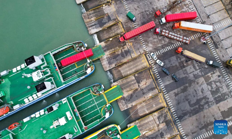 This aerial drone photo taken on Oct. 27, 2024 shows trucks driving onto a ro-ro ship at Xiuying Port in Haikou, south China's Hainan Province. The Xinhai Port, Xiuying Port and a railway port in Haikou resumed operation on Sunday afternoon as the impact of Typhoon Trami, this year's 20th typhoon, weakened. (Photo: Xinhua)