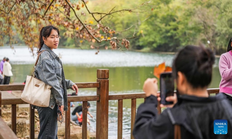 A tourist poses for photos at Huaxi National Urban Wetland Park in Guiyang, capital of southwest China's Guizhou Province, Oct. 27, 2024. (Photo: Xinhua)