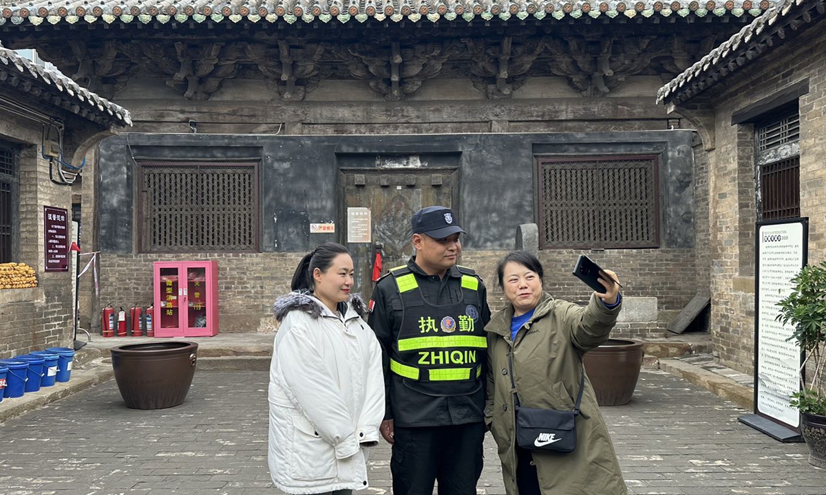 Visitors pose for photos with security guard Zhao Jianfei at Tiefo Temple after their tour, on October 17, 2024. Photo: Lin Xiaoyi/GT 