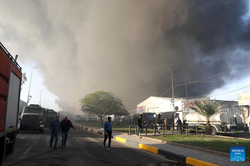 People pass by the fire scene at a warehouse in Baghdad, Iraq on Oct. 27, 2024. A fire broke out at a warehouse in Iraqi capital Baghdad on Sunday (Photo: Xinhua)