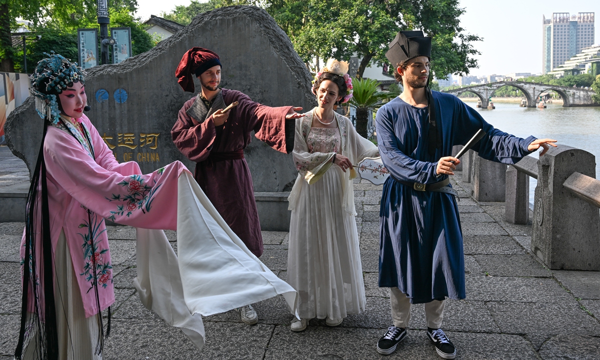 Three foreign members of the New Marco Polo Travelogue expedition team, dressed in traditional Chinese costumes, learn Chinese opera by the Grand Canal in Hangzhou, East China's Zhejiang Province, on June 15, 2024. Photo: VCG