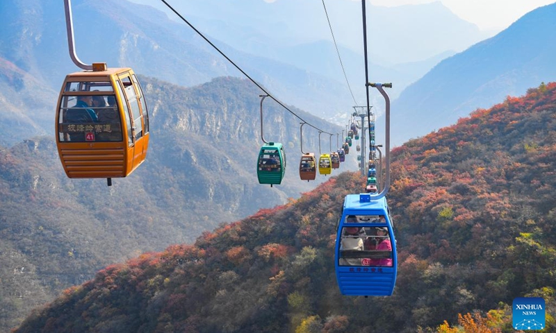 People take cable cars for sightseeing at the Pofengling scenic spot in Fangshan District of Beijing, capital of China, Oct. 29, 2024. The scenic spot has ushered in the best time of the year to view red leaves. More than 100,000 plants there are greeting visitors with their flame-like new attire. (Photo: Xinhua)