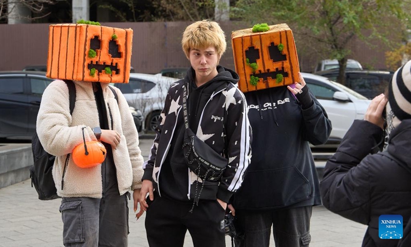 A pedestrian poses for photos with people in Halloween costumes on the street in Vladivostok, Russia, Oct. 31, 2024. (Photo: Xinhua)