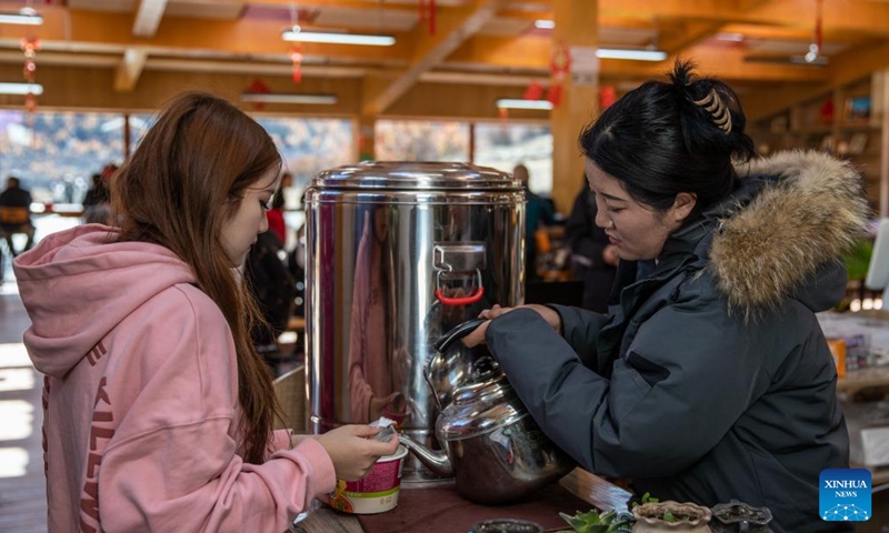 A staff member provides hot water to a tourist at a service station of Yading scenic spot in Daocheng County of Tibetan Autonomous Prefecture of Garze, southwest China's Sichuan Province, Oct. 31, 2024. (Photo: Xinhua)