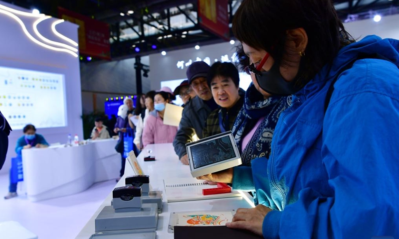 A visitor stamps commemorative seals on a notebook during the Beijing International Coin Exposition 2024 at the China National Convention Center in Beijing, capital of China, Nov. 1, 2024. (Photo: Xinhua)