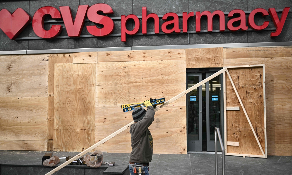 A worker boards up the windows of a CVS Pharmacy store near teh White House in Washington, DC on elecation day eve, November 4, 2024, to prepare for possible violence on or after the election. Photo: VCG   