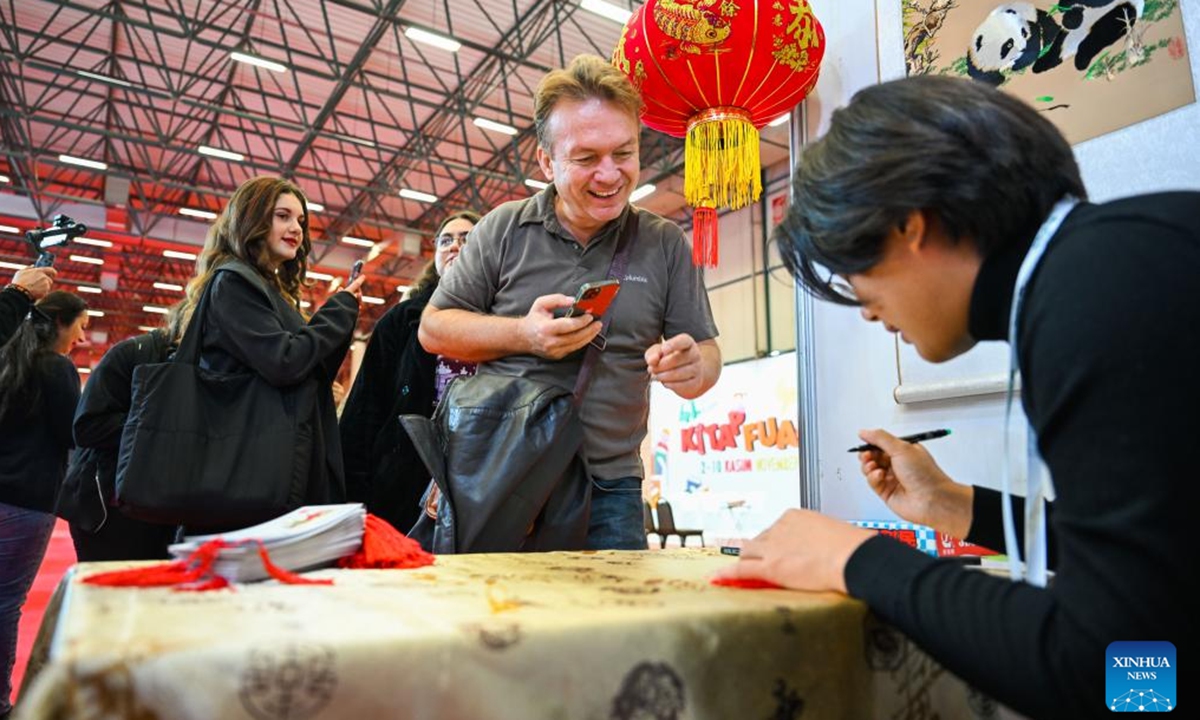 Visitors line up to receive bookmarks featuring Chinese culture at the 41st International Istanbul Book Fair in Istanbul, Türkiye, on Nov. 2, 2024. The Book Fair kicked off here on Saturday, featuring participation from Chinese publishers and a diverse selection of Chinese books. Running until Nov. 10, the fair hosts 12 Chinese publishers this year, who are expected to sign copyright agreements to foster cooperation with participants, according to the fair's website. (Photo: Xinhua)