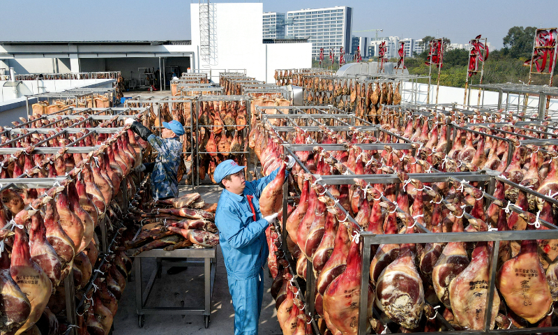 Workers check Jinhua ham that is hanging for drying in Jinhua, East China's Zhejiang Province, on December 3, 2024. Jinhua ham is a type of dry-cured ham named after the city of Jinhua, where it is produced. The production process of Jinhua ham has been passed down for thousands of years. Now is the best time for drying. After several other processing measures and about half a year of fermentation, the ham can be put on sale. Photo: VCG