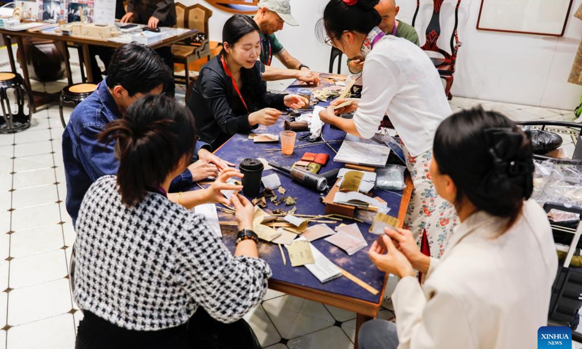 Media workers try lacquerware making at the media center of the 7th China International Import Expo (CIIE) in Shanghai, east China, Nov. 4, 2024. The 7th CIIE will be held in Shanghai from Nov. 5 to 10. A variety of cultural activities at the media center attracted many media staff. (Photo: Xinhua)