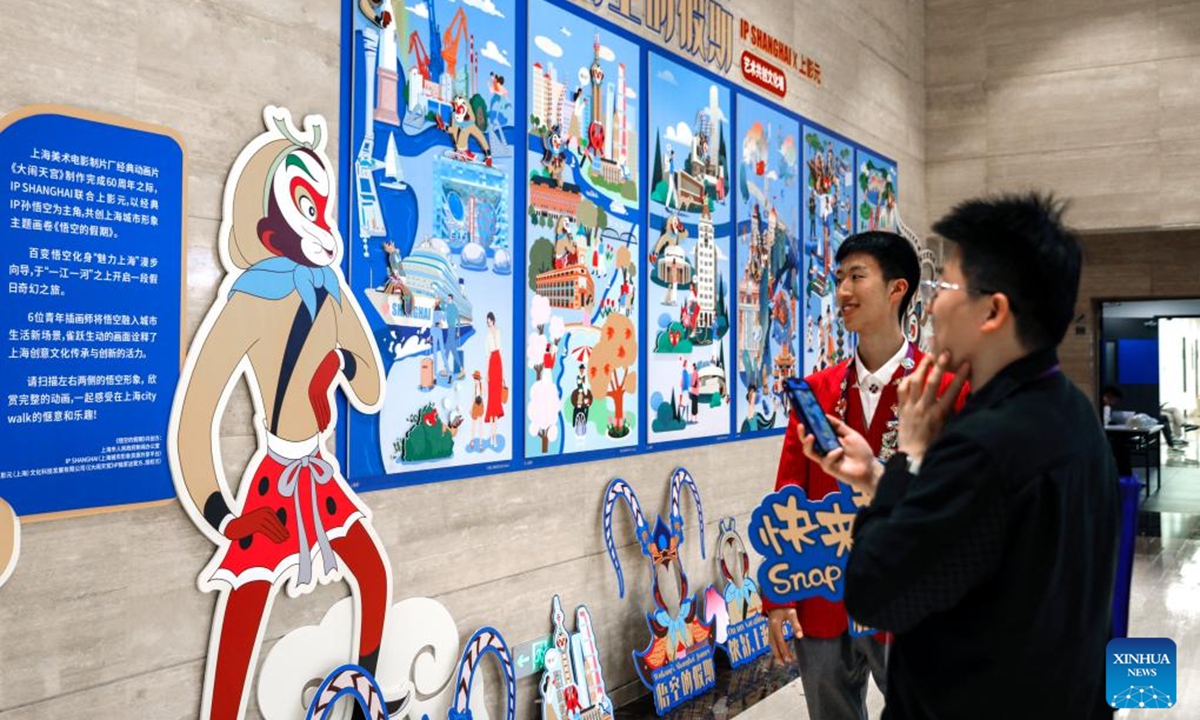 Media workers look at Wukong's Shanghai Journey, a comic themed on Shanghai, at the media center of the 7th China International Import Expo (CIIE) in Shanghai, east China, Nov. 4, 2024. The 7th CIIE will be held in Shanghai from Nov. 5 to 10. A variety of cultural activities at the media center attracted many media staff. (Photo: Xinhua)