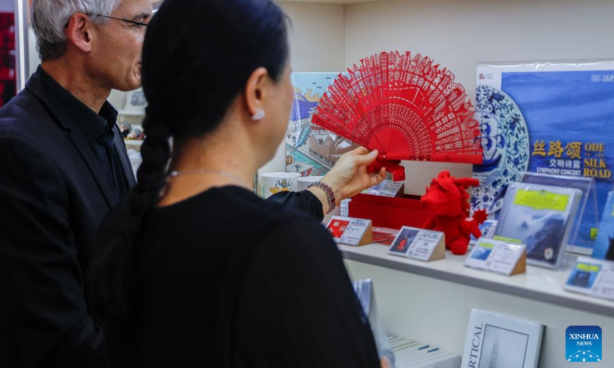 Artists watch cultural and creative products after their performance at the media center of the 7th China International Import Expo (CIIE) in Shanghai, east China, Nov. 4, 2024. The 7th CIIE will be held in Shanghai from Nov. 5 to 10. A variety of cultural activities at the media center attracted many media staff. (Photo: Xinhua)