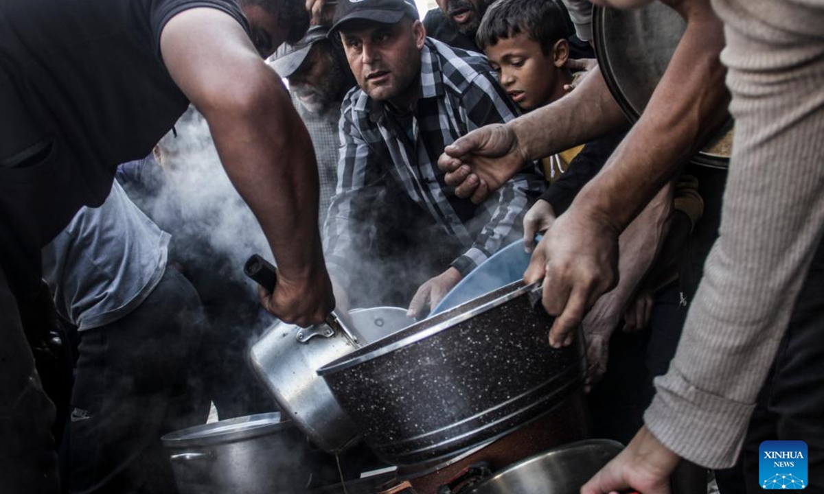 People receive food relief in Gaza City, on Nov. 4, 2024. The entire Palestinian population in North Gaza is at imminent risk of dying from disease, famine and violence, a joint statement signed by the heads of 15 UN agencies, including the World Health Organization, the UN Children's Fund, International Organization for Migration, the World Food Programme, and aid groups, said. (Photo: Xinhua)