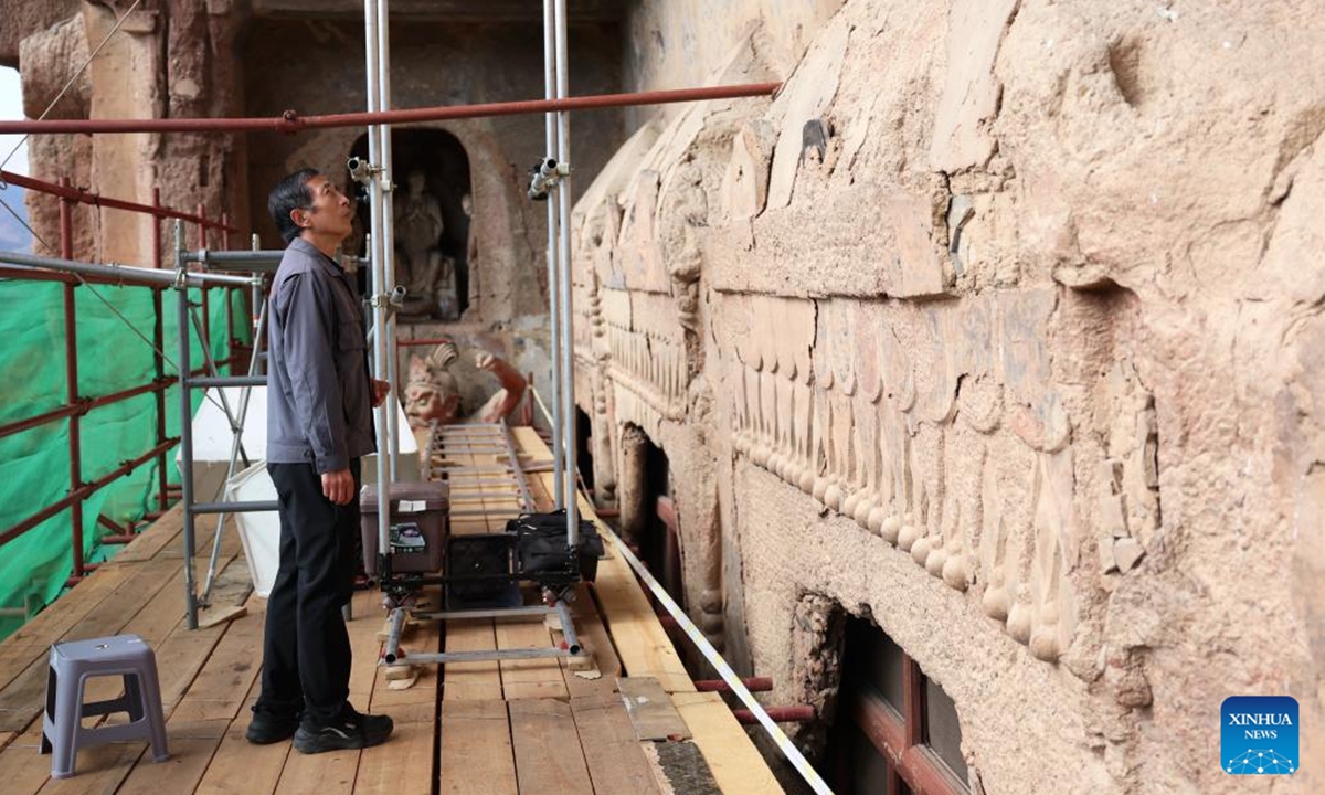 Dong Guangqiang, director of the digital center of Maiji Mountain Grottoes art institute, checks the mural sculptures at the Maiji Mountain Grottoes in Maiji District of Tianshui City, northwest China's Gansu Province on Nov. 2, 2024.   (Photo: Xinhua)