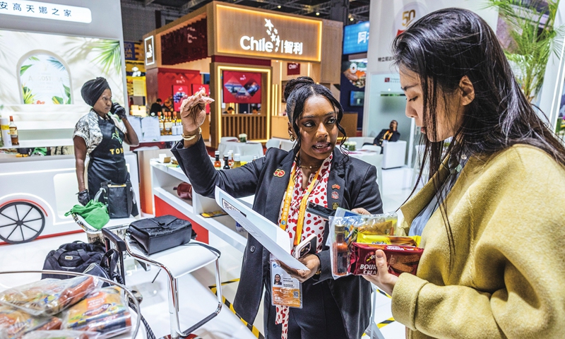 An exhibitor from Trinidad and Tobago talks with a visitor at the 7th CIIE in Shanghai on November 6, 2024. The expo has attracted 3,496 exhibitors from 129 countries and regions. Photo: Li Hao/GT