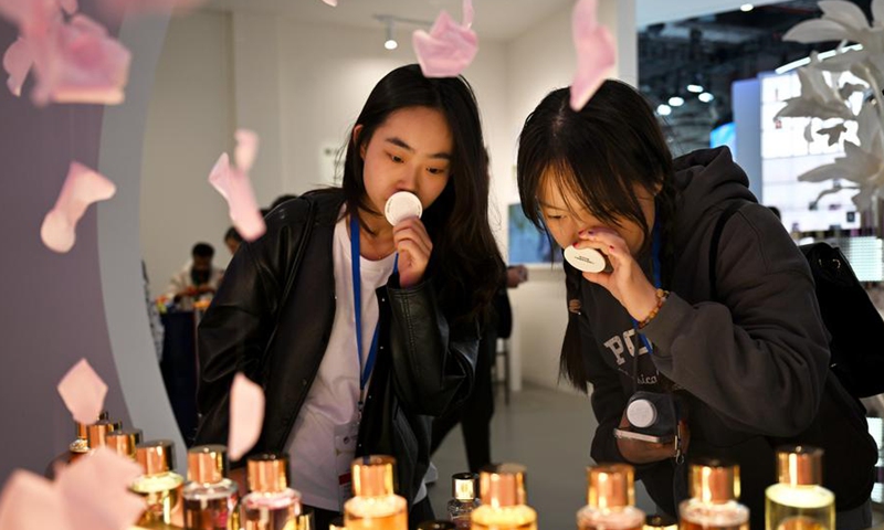 Visitors try perfume at the booth of L'Oreal, a full-time attender of the China International Import Expo (CIIE), during the 7th CIIE in east China's Shanghai, Nov. 9, 2024. (Photo by Chen Haoming/Xinhua)