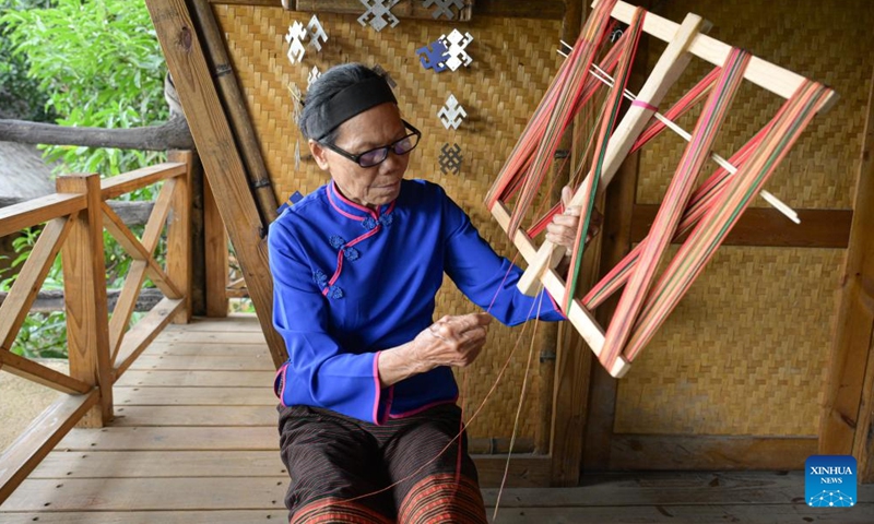 A senior Li woman demonstrates a traditional thread winding technique at Binglanggu tourism area in Baoting Li and Miao Autonomous County, south China's Hainan Province, Nov. 4, 2024. (Photo: Xinhua)