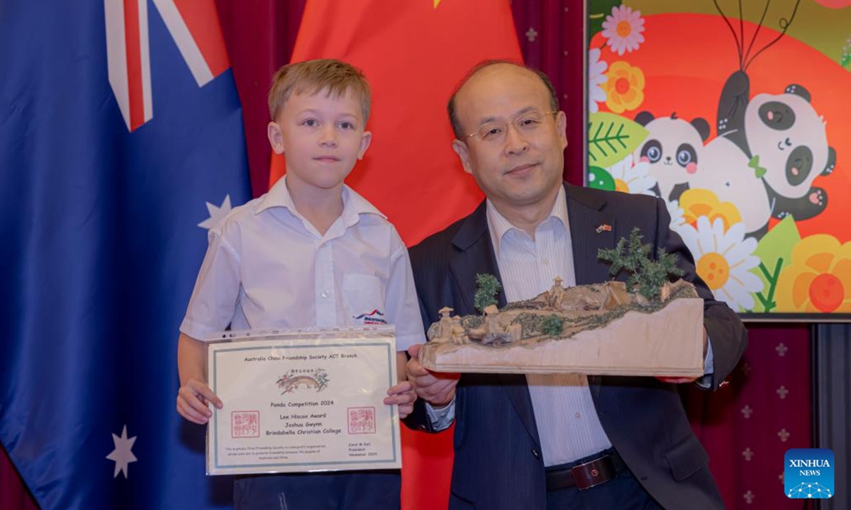 Chinese Ambassador to Australia Xiao Qian poses for photos with a prize winner during the Panda Competition at the Chinese Embassy in Australia, in Canberra, Australia on Nov. 6, 2024. Australian children in Canberra were awarded on Wednesday for their paintings, sculptures, poems, creative collage and constructions surrounding the subject of the Chinese and the Australian gold rushes.  (Photo: Xinhua)