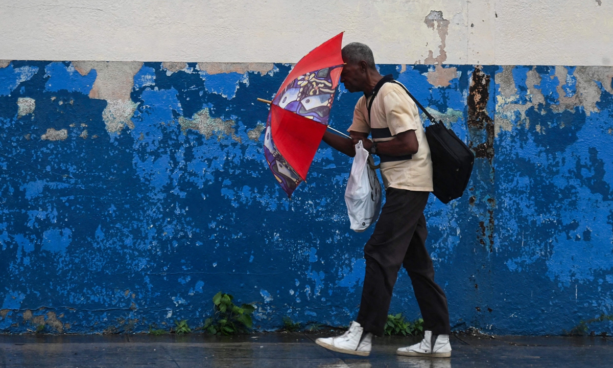 A man with an umbrella walks along a street after Hurricane Rafael makes landfall in Havana on November 6, 2024. Hurricane Rafael knocked out power to all of Cuba the previous day as it made landfall on the island still reeling from a recent blackout and a previous major storm, the national power company said. Photo: VCG