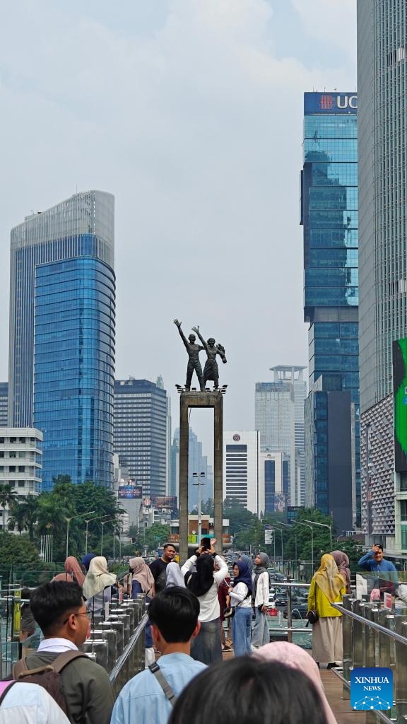 This photo taken with a mobile phone shows people taking photos with Selamat Datang Monument on a nearby observation deck in Jakarta, Indonesia, July 10, 2024. Located on the northwest coast of Java Island, Jakarta is the largest city in Indonesia and is currently the political, economic and cultural center of the country.   (Photo: Xinhua)