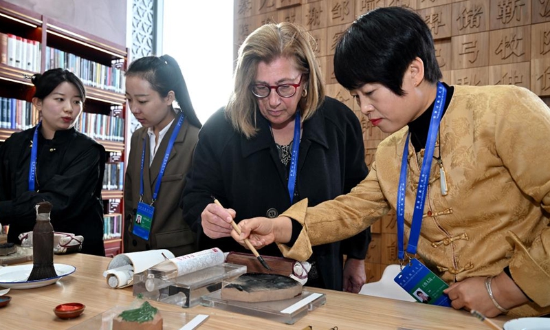 A foreign visitor (2nd R) experiences woodblock printing during an exhibition on classical studies achievements in Beijing, capital of China, on Nov. 7, 2024. The exhibition opened here on Thursday, as one of the auxiliary activities of the World Conference of Classics scheduled from Nov. 6 to 8 in Beijing. (Photo: Xinhua)