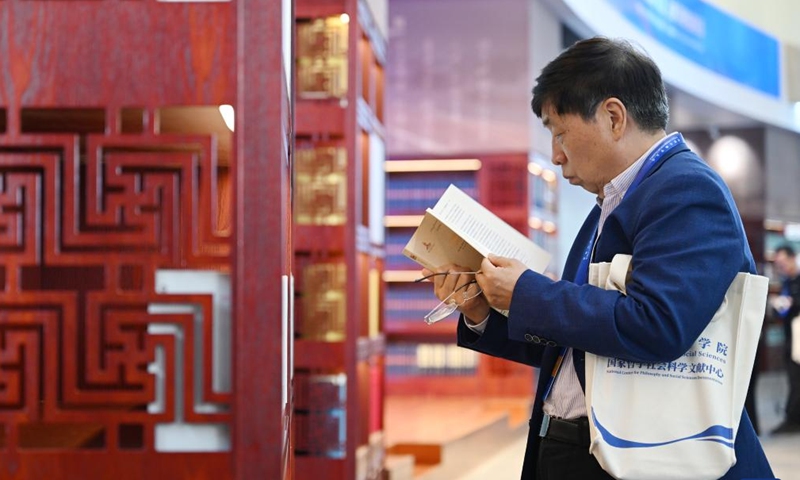 A visitor reads books during an exhibition on classical studies achievements in Beijing, capital of China, on Nov. 7, 2024. The exhibition opened here on Thursday, as one of the auxiliary activities of the World Conference of Classics scheduled from Nov. 6 to 8 in Beijing. (Photo: Xinhua)