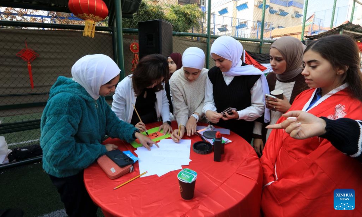 Students learn to use chopsticks during a culture event held in Amman, Jordan on Nov. 7, 2024. A cultural event organized by the TAG Confucius Institute in Jordan was held in Amman on Thursday, providing Chinese cultural experience activities for teachers and students.  (Photo: Xinhua)