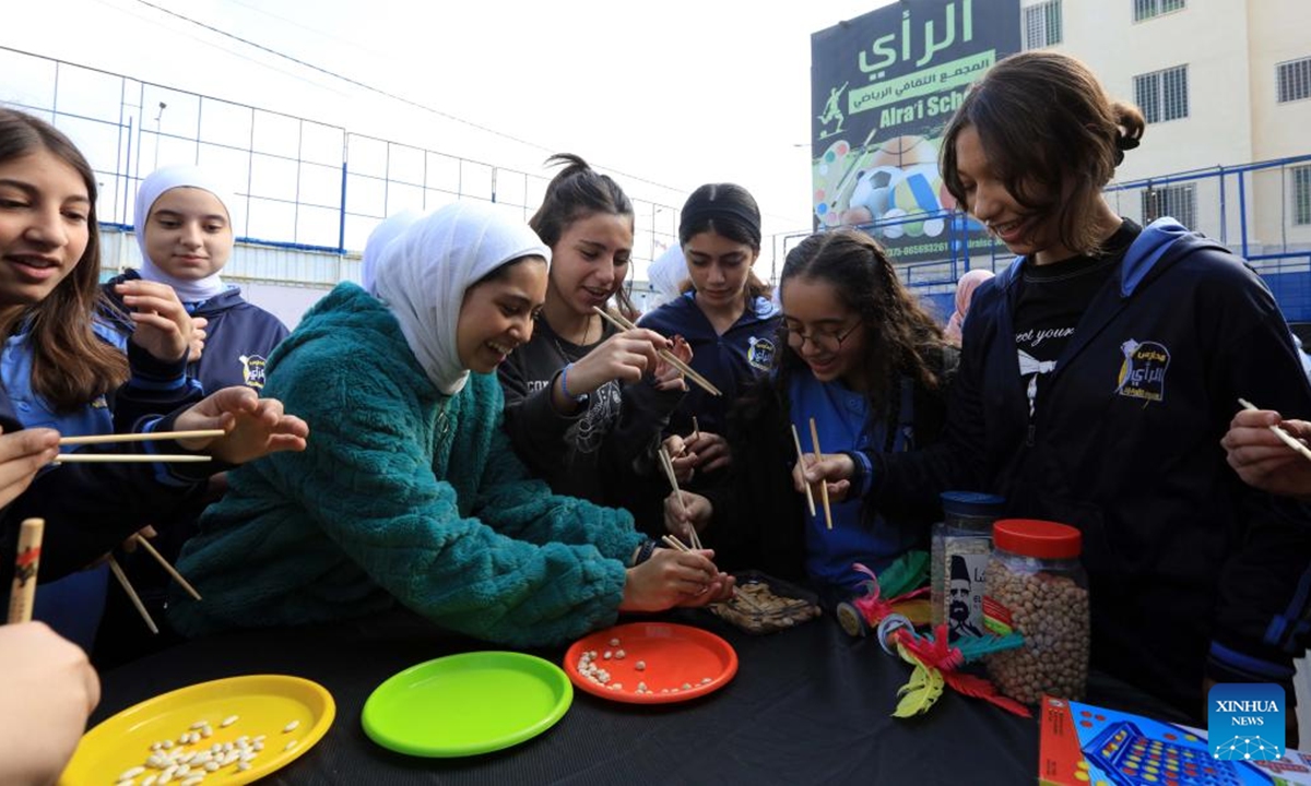 Students learn to use chopsticks during a culture event held in Amman, Jordan on Nov. 7, 2024. A cultural event organized by the TAG Confucius Institute in Jordan was held in Amman on Thursday, providing Chinese cultural experience activities for teachers and students.  (Photo: Xinhua)