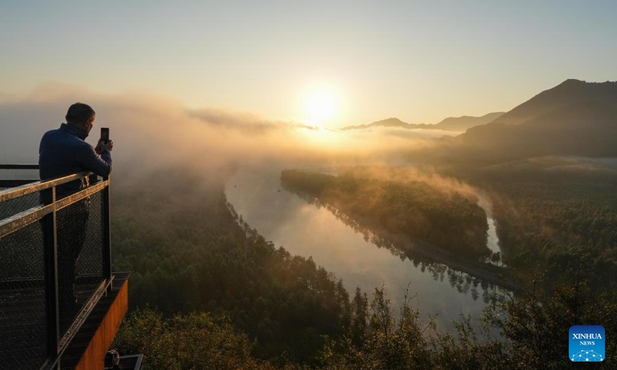 A tourist takes photos on a viewing platform during sunrise near a wetland park in Fangtang Township of Ningguo City, east China's Anhui Province, Nov. 7, 2024.  (Photo: Xinhua)