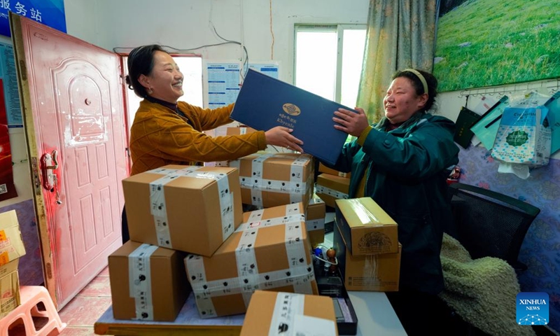 Dawa Drolma (L) passes a package to a staff member of a post service station in Maisu Town of Dege County in Garze Tibetan Autonomous Prefecture, southwest China's Sichuan Province, Nov. 4, 2024. (Photo: Xinhua)