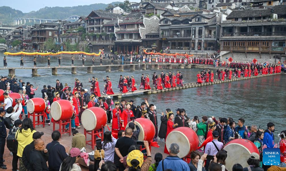 The newlyweds dressed in wedding costumes parade in Fenghuang ancient town in Xiangxi Tujia and Miao Autonomous Prefecture, central China's Hunan Province, Nov. 11, 2024. A hundred couples from all over China attended a mass wedding ceremony at Fenghuang ancient town on Monday.   (Photo: Xinhua)