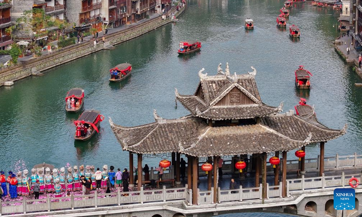 An aerial drone photo taken on Nov. 11, 2024 shows the newlyweds taking boats to parade in Fenghuang ancient town in Xiangxi Tujia and Miao Autonomous Prefecture, central China's Hunan Province. A hundred couples from all over China attended a mass wedding ceremony at Fenghuang ancient town on Monday.    (Photo: Xinhua)