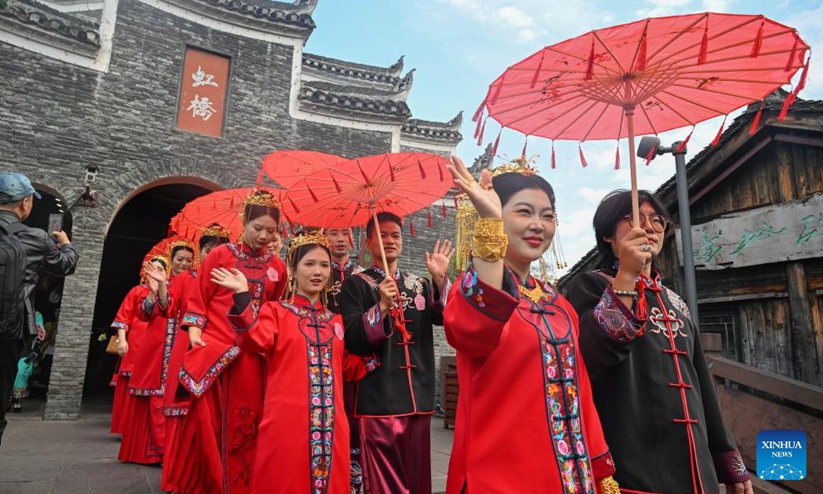 The newlyweds dressed in wedding costumes parade in Fenghuang ancient town in Xiangxi Tujia and Miao Autonomous Prefecture, central China's Hunan Province, Nov. 11, 2024. A hundred couples from all over China attended a mass wedding ceremony at Fenghuang ancient town on Monday.  (Photo: Xinhua)