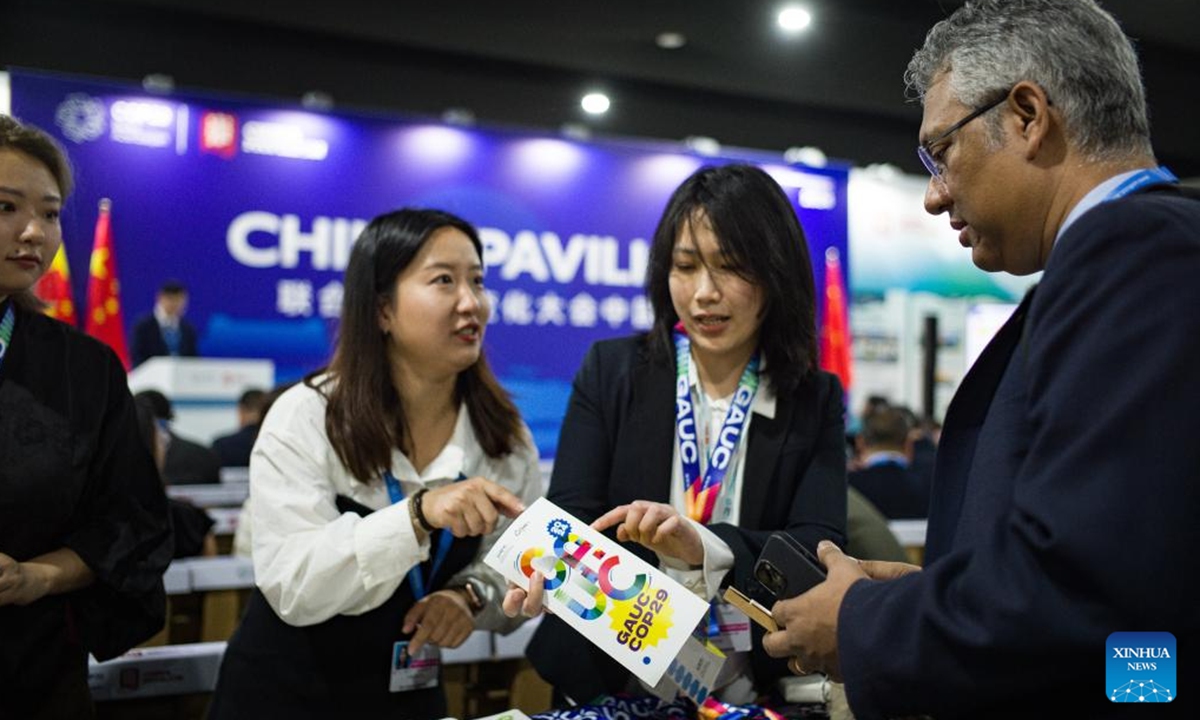 Staff members brief a pamphlet to a guest during a side meeting marking the opening of the China Pavilion at the 29th session of the Conference of the Parties to the United Nations Framework Convention on Climate Change (UNFCCC), or COP29, in Baku, Azerbaijan, Nov. 11, 2024.  (Photo: Xinhua)