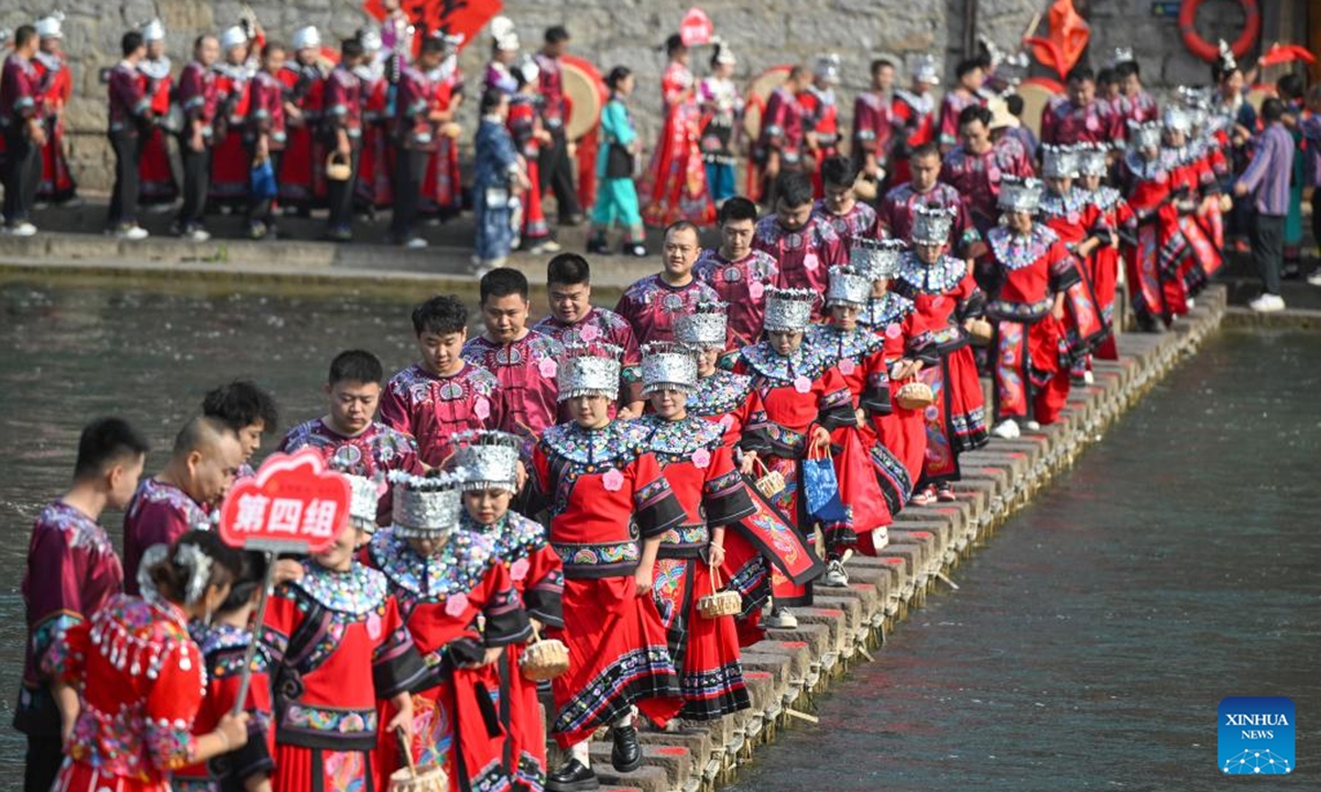 The newlyweds dressed in wedding costumes parade in Fenghuang ancient town in Xiangxi Tujia and Miao Autonomous Prefecture, central China's Hunan Province, Nov. 11, 2024. A hundred couples from all over China attended a mass wedding ceremony at Fenghuang ancient town on Monday. (Photo: Xinhua)