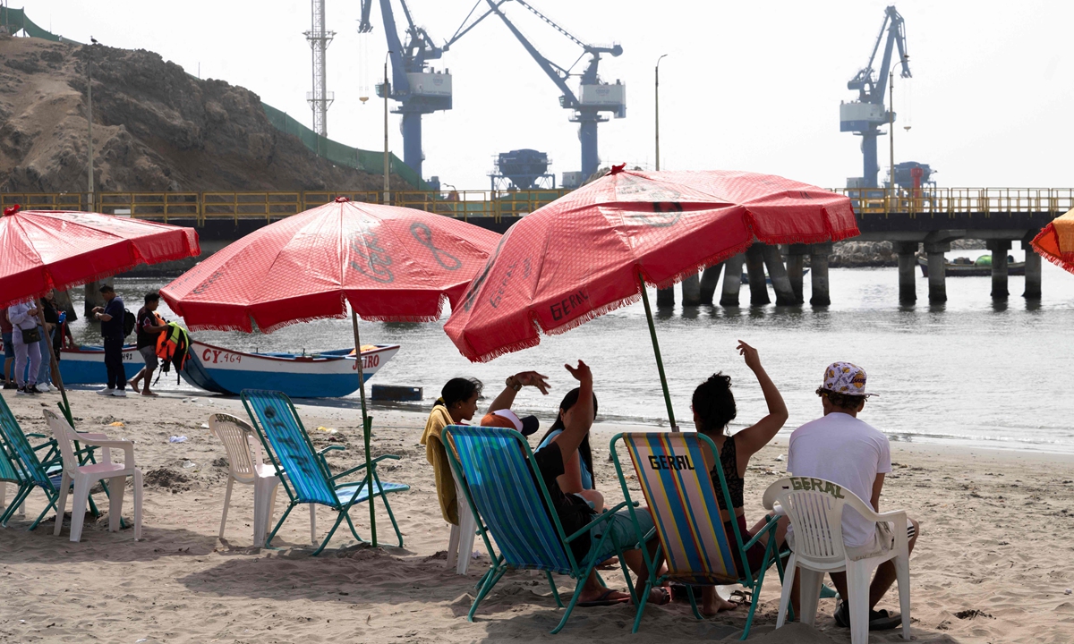 Residents relax and enjoy the beach under the sun, as cranes build Chancay Port in the background in Lima, Peru, on October 29, 2024. Photo: VCG