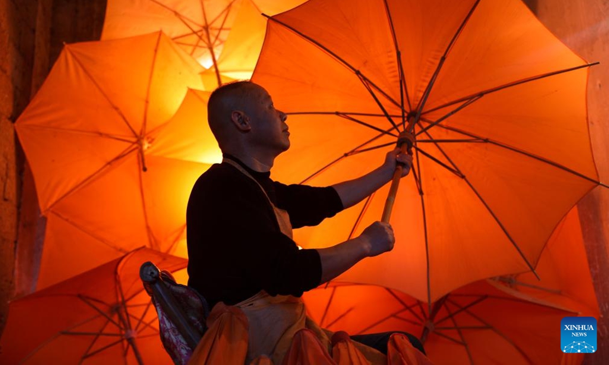 Zheng Guomin, a provincial-level inheritor of intangible cultural heritage, checks an oilcloth umbrella at Guomin Oilcloth Umbrella Plant in Gufeng Village of Jingxian County, east China's Anhui Province, Nov. 13, 2024. The umbrella, made of oiled cloth and bamboo frame, is a traditional Chinese handicraft.  (Photo: Xinhua)