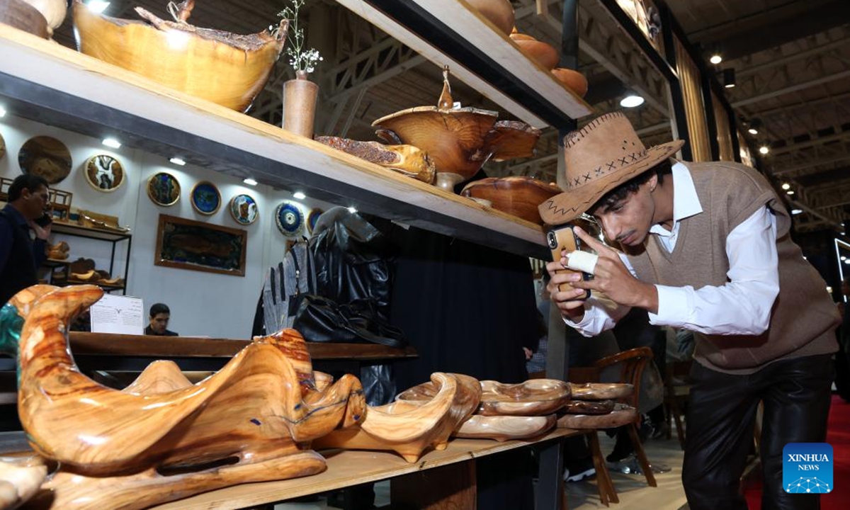 A visitor takes photos of handicrafts displayed during the 37th National Handicrafts Exhibition in Tehran, Iran, Nov. 13, 2024. The exhibition opened here Wednesday. (Xinhua)