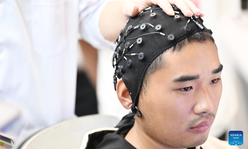 An undergraduate puts on an elastic electroencephalogram cap at a laboratory in Tianjin University in Tianjin, north China, Nov. 15, 2024. Tianjin University enrolled the first batch of freshmen majored in brain-machine interface (BMI), with interdisciplinary courses ranging from the basic theory of brain-machine interaction to device system development, transformation and application. (Photo: Xinhua)