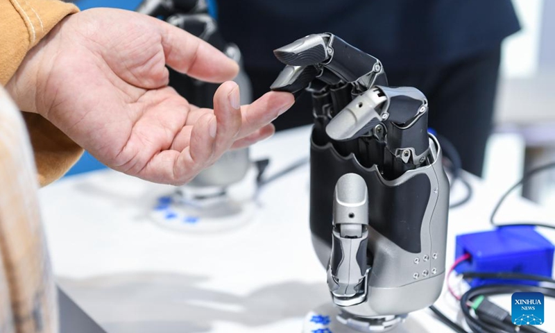 A visitor touches the finger of a mechanical hand at a booth at the 26th China High-Tech Fair (CHTF) in Shenzhen, south China's Guangdong Province, Nov. 15, 2024. A variety of robots and products of related industries are exhibited at the ongoing 26th CHTF, attracting lots of attention. (Photo: Xinhua)