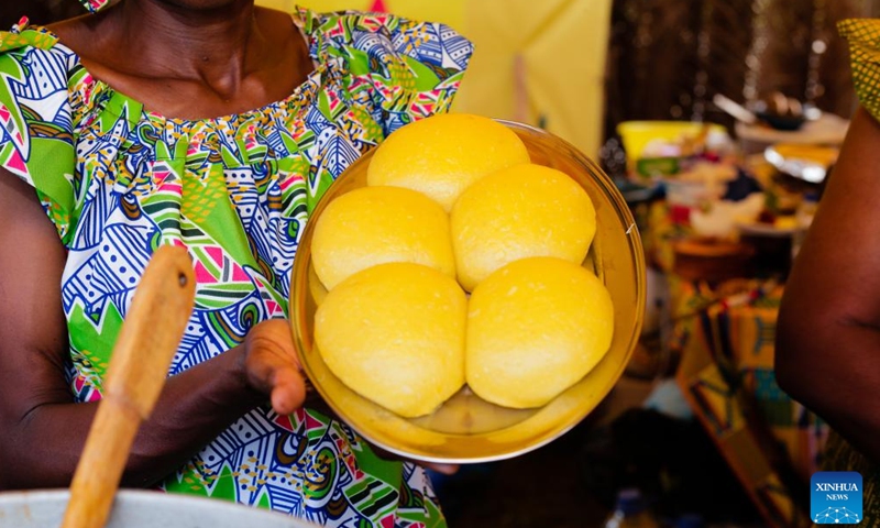 This photo taken on Nov. 15, 2024 shows a woman presenting a plate of Ivorian dish Foutou banane, which is made from plantain mixed with boiled and crushed cassava, during an African culture promotion festival in Abidjan, Cote d'Ivoire. (Photo by Laurent Idibouo/Xinhua)