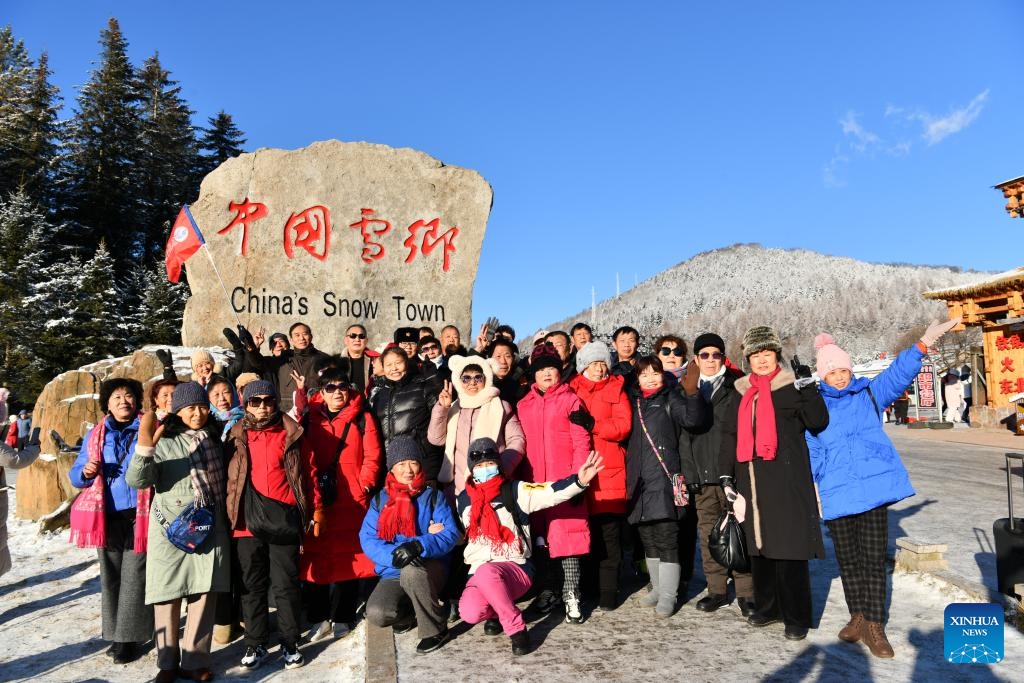 Tourists pose for a photo in front of the tablet of China's Snow Town scenic spot in Mudanjiang, northeast China's Heilongjiang Province, Nov. 17, 2024. The China's Snow Town scenic spot opened to the public on Sunday. (Photo by Wang Yanlong/Xinhua)