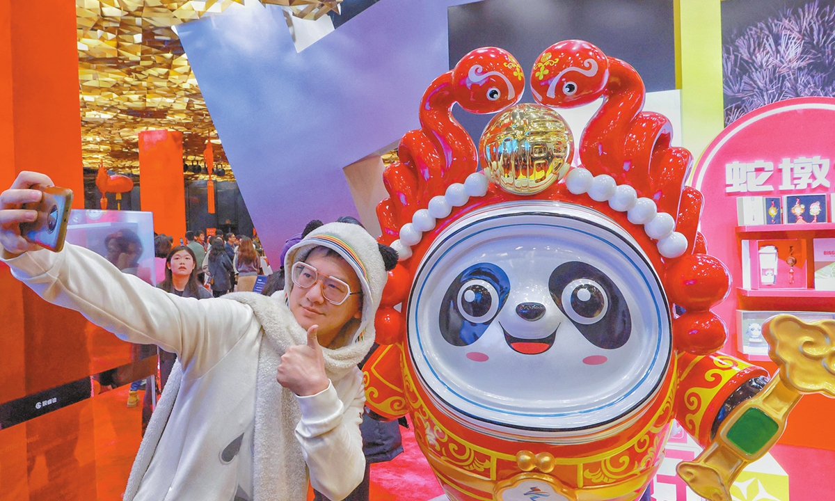 A person takes a photo with a snake-themed mascot of Bing Dwen Dwen in Beijing on November 19, 2024. Following the tiger, rabbit and Chinese dragon versions of Bing Dwen Dwen in recent years, a snake-themed mascot of the 2022 Beijing Winter Olympic Games was unveiled in Beijing on the day. Photo: VCG